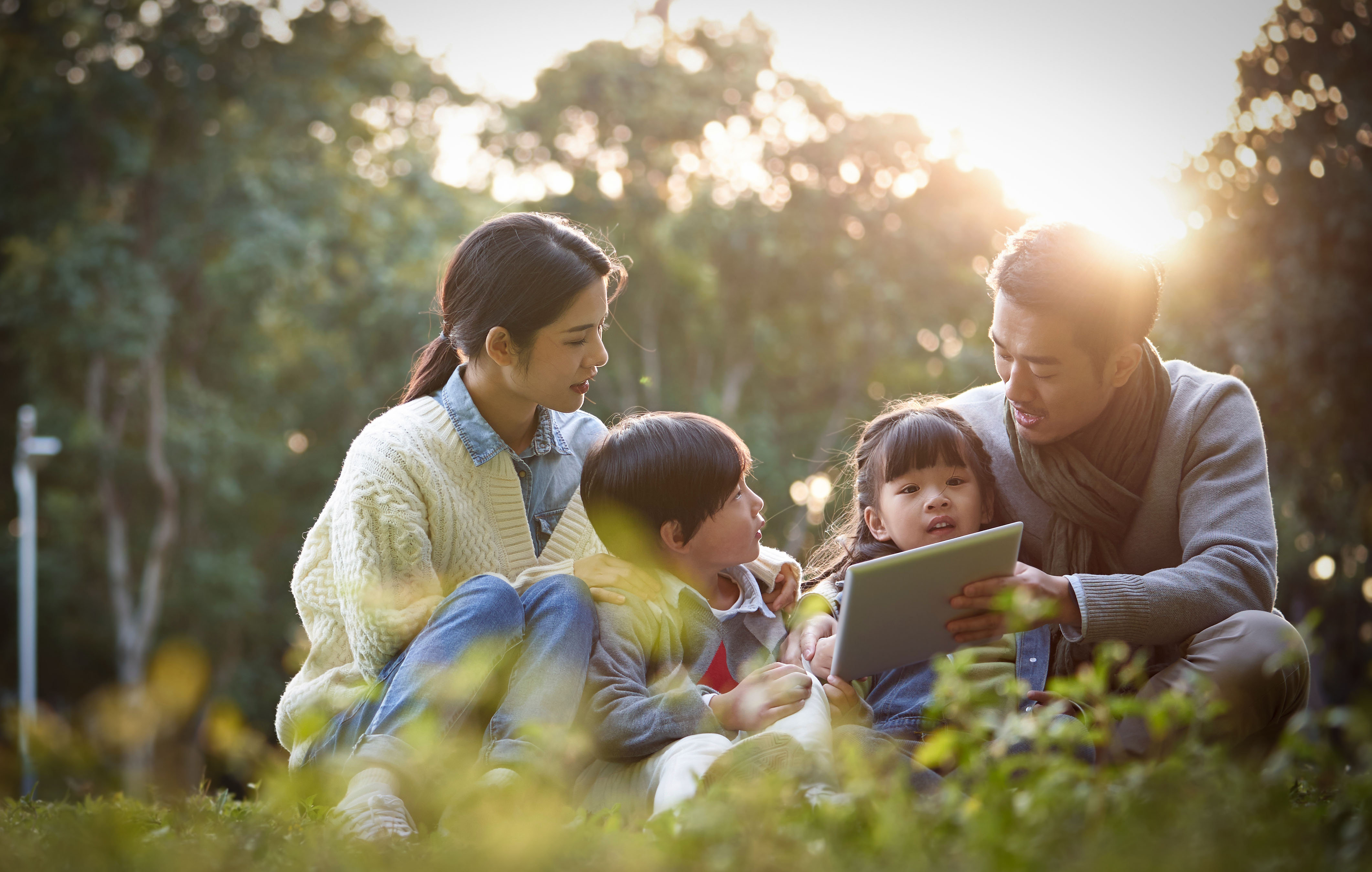 happy asian family having a good time outdoors in city park Family with kids waving american flags
